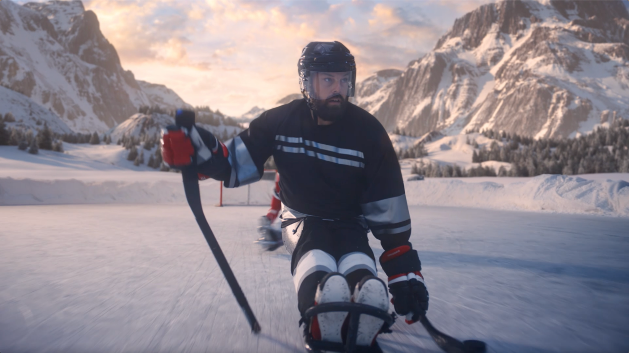 Параолимпийски състезател по хокей се състезава по леда със стик в ръка