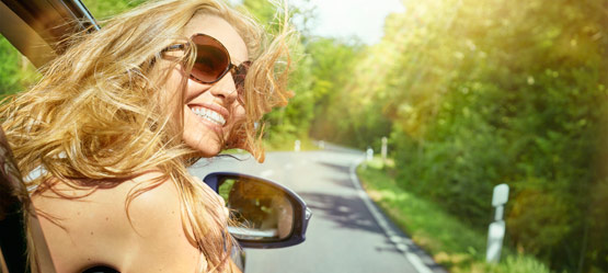Happy woman leaning out car window 